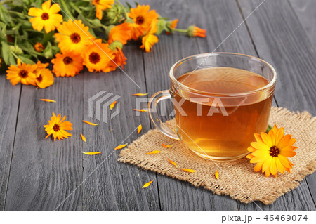 Calendula tea with fresh flowers on black wooden background 46469074
