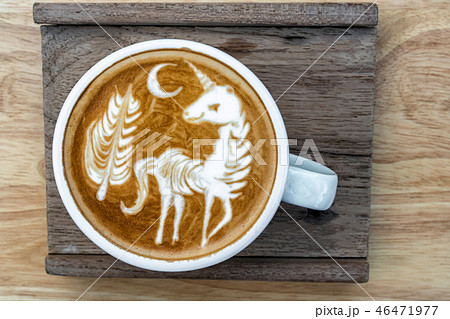 A Cup of coffee with latte art menu which show the unicorn and tree with moon on the wooden table background, drink and art concept 46471977