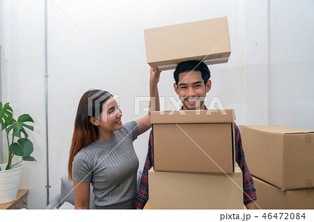 Asian young couple carrying big cardboard box for moving in new house, Helping relocate and joshing together, Moving and House Hunting concept 46472084