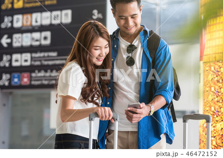 Asian couple traveler using the smart mobile phone for check-in at the flight information screen in modern an airport, travel and transportation with technology concept. 46472152