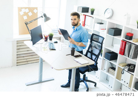 A young man standing in the office and working at the computer table. A young man standing in the office and working at the computer table. 46478471