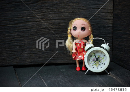 Clock with a girl doll placed on an old wooden. 46478656