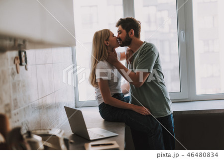 Lovely kissing couple spending time at home in kitchen Lovely kissing couple spending time at home in kitchen 46480834