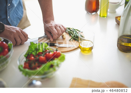 Man crushing garlic with the flat of a knife on cutting board 46480852