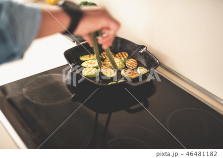 Man cooking slices of zucchini on frying pan Man cooking slices of zucchini on frying pan 46481182