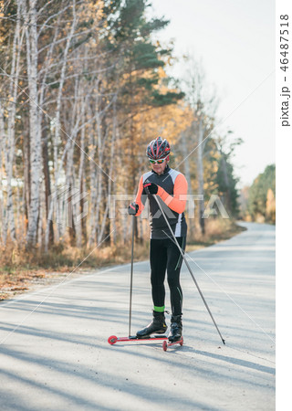 Training an athlete on the roller skaters. Biathlon ride on the roller skis with ski poles, in the 46487518