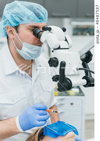 Doctor used microscope. Dentist is treating patient in modern dental office. Operation is carried 46487597