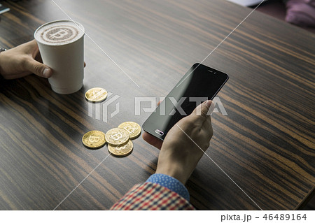 Rich man holding a bitcoin coin and drinking a coffee with a phone and gold coins of bitcoin on a 46489164