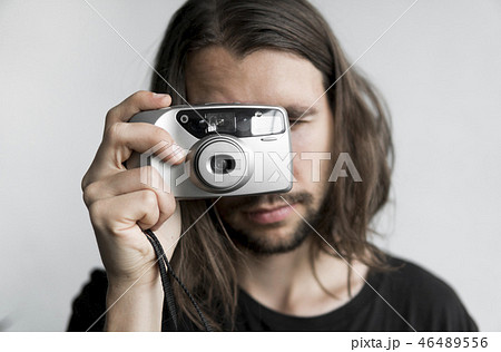 Handsome young bearded man with a long hair and in a black shirt holding vintage old-fashioned film 46489556