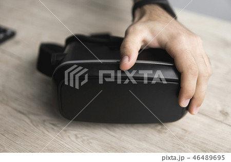 VR virtual reality glasses on a table with a man hand. 46489695