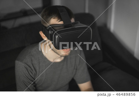Young bearded man wearing headset of virtual reality in office sitting on a sofa. Young bearded man wearing headset of virtual reality in office sitting on a sofa. 46489856