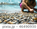 Waves washing over gravel beach and playing kid, macro shot with narrow focus background 46490930