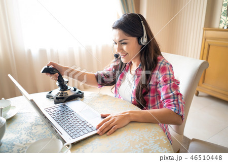 Pretty woman plays games with a retro joystick on laptop Pretty woman plays games with a retro joystick on laptop 46510448