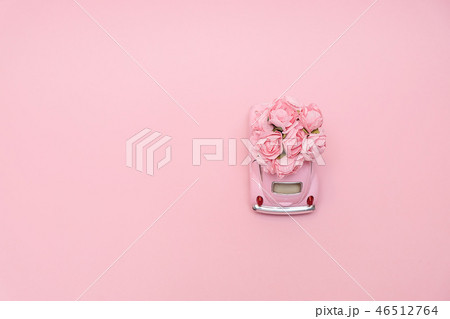 Pink retro toy car delivering bouquet of flowers 46512764