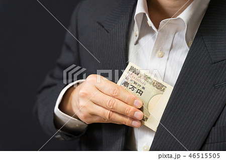 札束を懐に収めるビジネスマンの写真素材