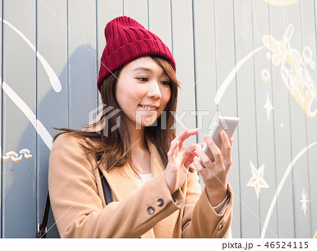 壁にもたれてスマホを操作する女性 壁にもたれてスマホを操作する女性 46524115