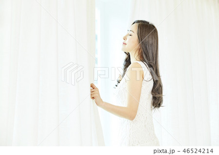 若い女性 窓 カーテン 46524214