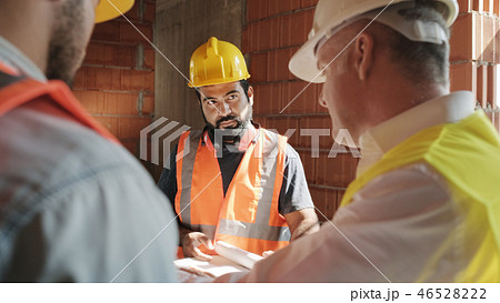 Supervisor Showing Building Plans To Workers In New House 46528222