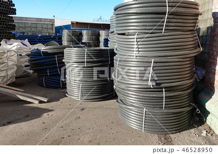 Coiled black plastic pipes stored outdoors Coiled black plastic pipes stored outdoors 46528950