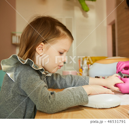 Little girl in nail salon receiving manicure by beautician. Little girl getting manicure at beauty 46531791