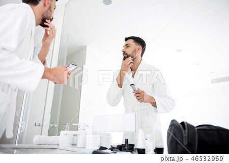 Calm man touching his beard in front of the bathroom Calm man touching his beard in front of the bathroom 46532969