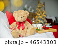 Two teddy bears siting on the bed with red candys near christmas tree. 46543303