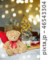 Two teddy bears siting on the bed with red candys near christmas tree. 46543304