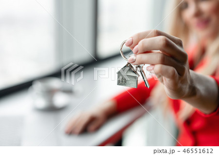 Mortgage concept. Woman in red coral business suit holding key with house shaped keychain. Modern Mortgage concept. Woman in red coral business suit holding key with house shaped keychain. Modern 46551612