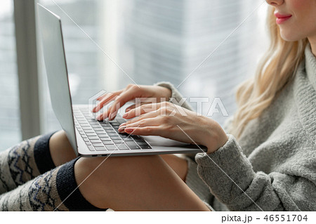 Girl typing on the keyboard. Beautiful blonde woman sitting on the bed and looks at the laptop Girl typing on the keyboard. Beautiful blonde woman sitting on the bed and looks at the laptop 46551704