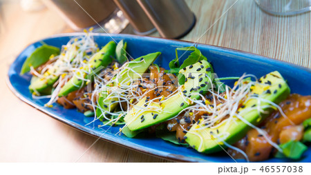 Delicious salmon tartare garnish with avocado on blue plate Delicious salmon tartare garnish with avocado on blue plate 46557038