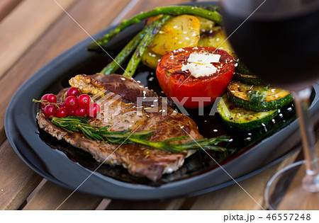 Roasted veal steak with vegetables and redcurrant on wooden surface 46557248