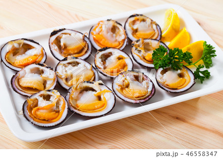 Deliciously salad of raw dog cockle with lemon and greens at plate 46558347