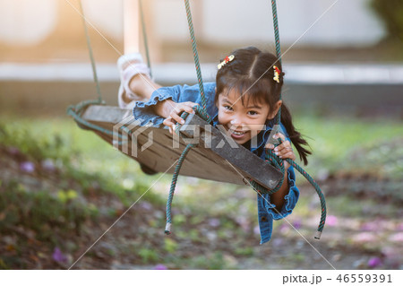 Happy asian child girl play on wooden swings 46559391