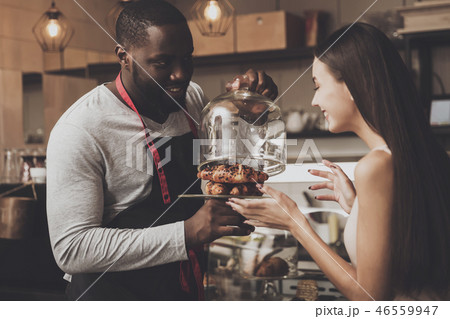 Male barista helps a girl to choose a dessert Male barista helps a girl to choose a dessert 46559947