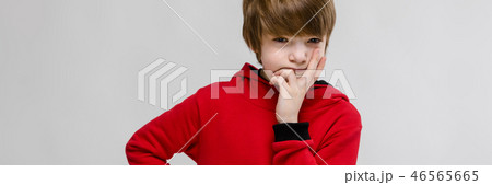 Cute confident caucasian suspicious little boy in red sweater on grey background Cute confident caucasian suspicious little boy in red sweater on grey background 46565665
