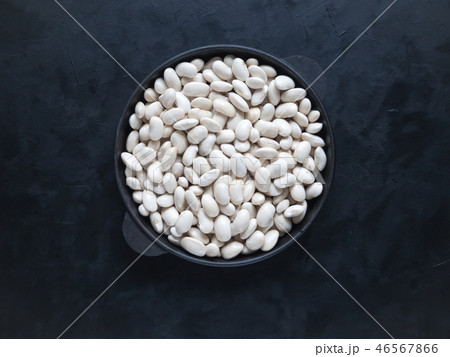 White beans in a frying pan on a black table. 46567866