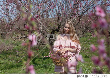 beautiful blonde woman collects pink flowers in a basket 46570546