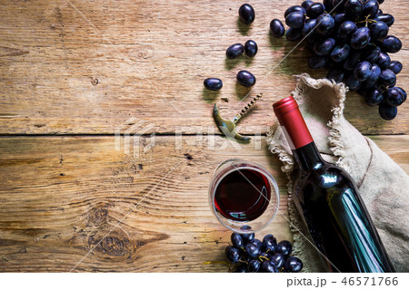 A bottle of red wine with grapes 46571766