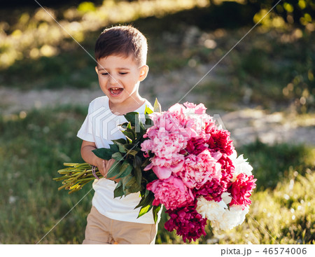Small boy carries a large bouquet of peonies. Small boy carries a large bouquet of peonies. 46574006