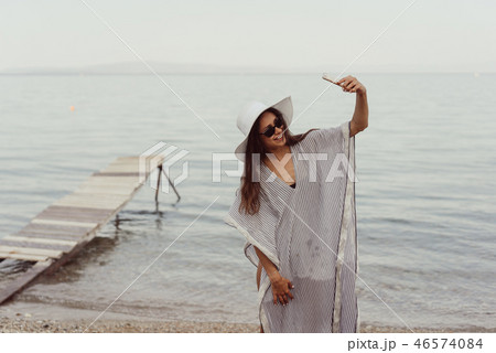 Cheerful young girl in summer hat and swimwear taking a selfie 46574084