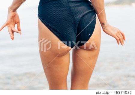 Close-up sexy ass of sporty girl wearing beautiful black swimsuit at the beach. Close-up sexy ass of sporty girl wearing beautiful black swimsuit at the beach. 46574085