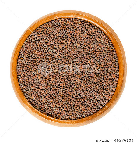 Black mustard seeds in wooden bowl over white Black mustard seeds in wooden bowl over white 46576104