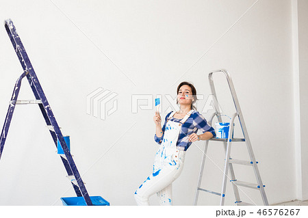 Repair, renovation, new home and people concept - young woman doing redecoration over white wall Repair, renovation, new home and people concept - young woman doing redecoration over white wall 46576267