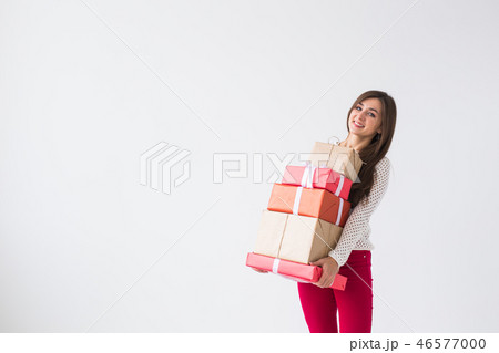 Christmas and holidays concept - young woman holding stack of gift boxes over white background with 46577000