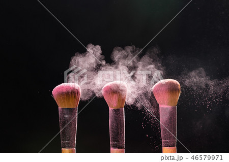 make up, beauty, mineral cosmetic concept - brush brushing away pink powder from another over the 46579971