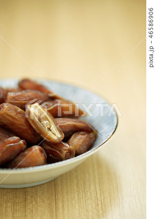 Sweet dried dates fruit in a bowl and on the table 46586906