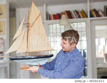 Hobby, collecting, ship and people concept - handsome man holding layout of a sailboat 46591021