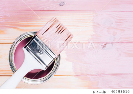White brush on open can of pink color on painting wooden board. White brush on open can of pink color on painting wooden board. 46593616