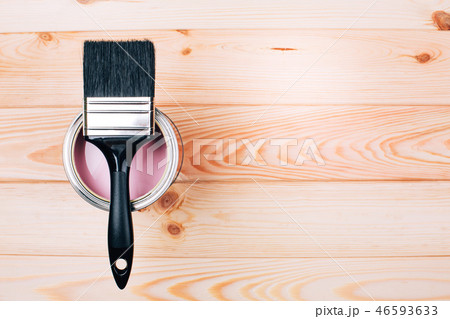 Brush on open can of pink color of paint on natural wooden board. Brush on open can of pink color of paint on natural wooden board. 46593633