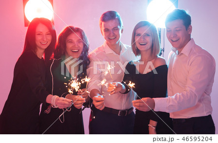 Celebrating with fun. Group of cheerful young men and women carrying sparklers. New year, holidays Celebrating with fun. Group of cheerful young men and women carrying sparklers. New year, holidays 46595204